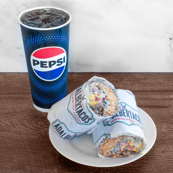 Two Adalbertacos burritos filled with rice, meat, and cheese, next to a Pepsi drink.