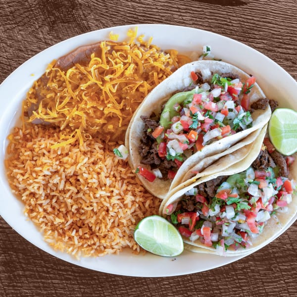 Two Adalbertacos carne asada tacos with pico de gallo, guacamole, rice, and refried beans.