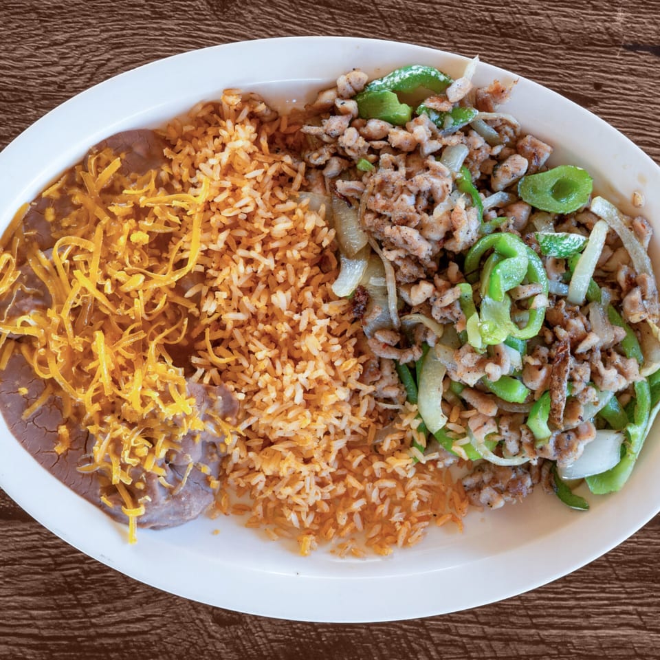 Adalbertacos Mexican Food plate with rice, refried beans with cheese, and fajita meat with peppers.